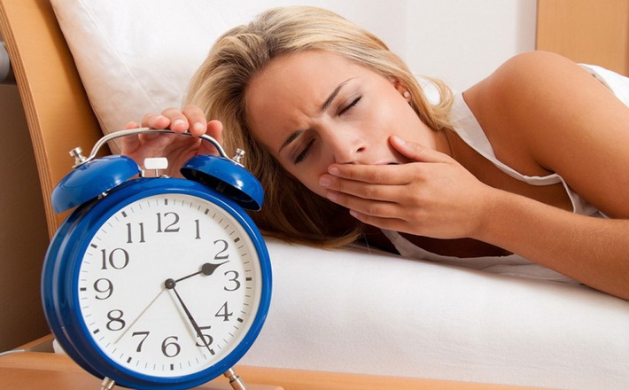 Schlaflos mit Uhr in der Nacht. Frau kann nicht schlafen.